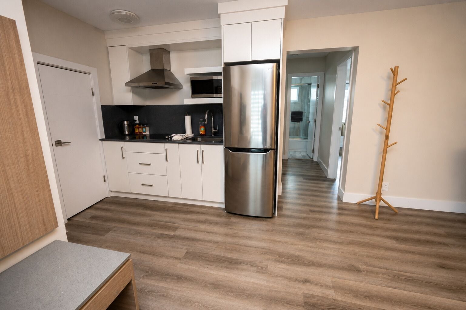 Eine moderne Küche mit weißen Schränken, einem Edelstahlkühlschrank und Holzboden.