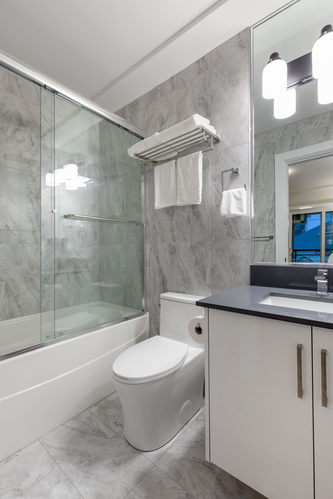Un baño moderno con ducha de vidrio, inodoro blanco y tocador con espejo.