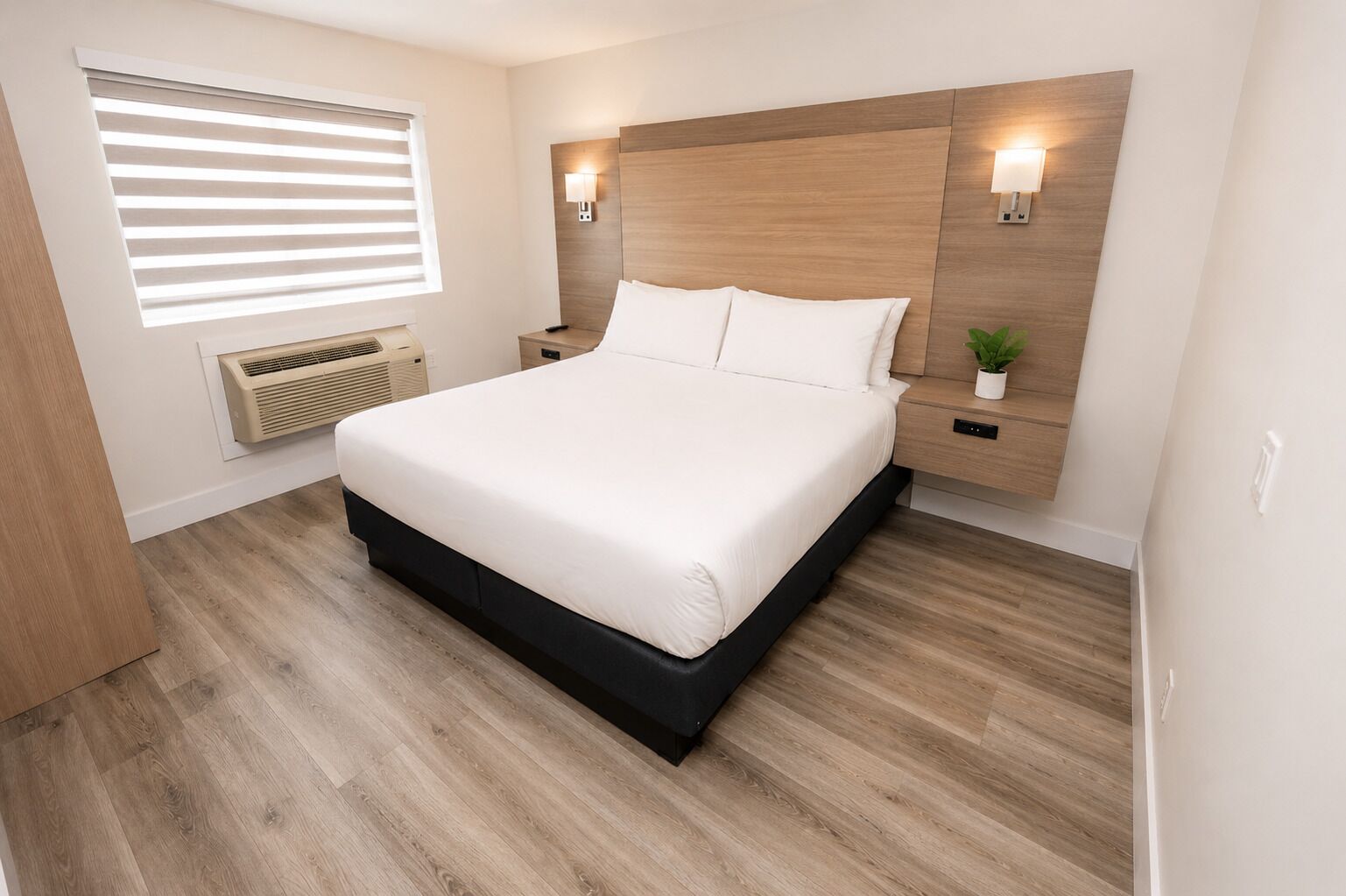 A neatly arranged bedroom with a bed, bedside tables, wall-mounted lights, and a window with blinds.
