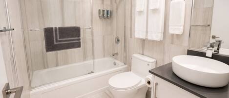 A modern bathroom with a glass-enclosed shower, a white toilet, and a round sink.