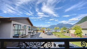 A hotel with a parking lot, a mountain view, and a clear sky.