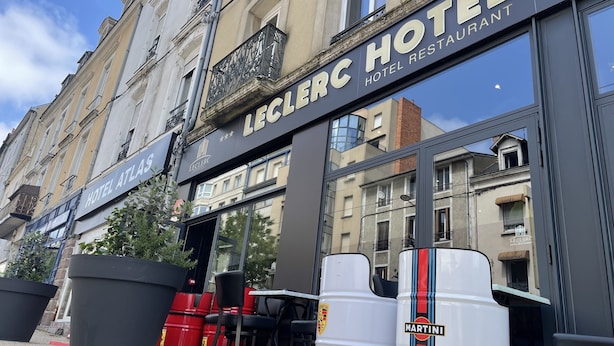 The exterior of Leclerc Hotel Restaurant, featuring large windows, a modern facade, and outdoor seating with potted plants. - Leclerc hôtel (Le Mans)