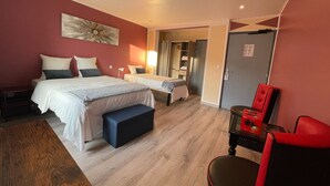 Une chambre d’hôtel avec deux lits, un bureau, une chaise et une armoire.