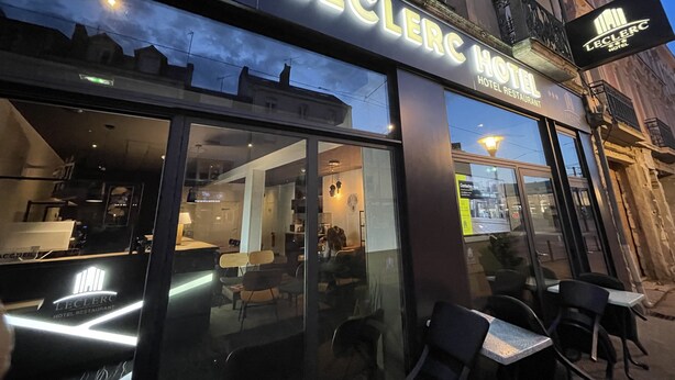La façade de l’hôtel-restaurant Leclerc, avec sa terrasse extérieure visible à travers les portes vitrées.