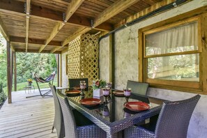 Enjoy al fresco dining in a serene outdoor setting with a long dining table and comfortable wicker chairs.