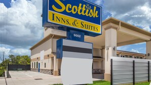 Une enseigne d’hôtel indiquant « Scottish Inns & Suites », offrant une vue dégagée sur l’entrée de l’établissement et sur le parking.