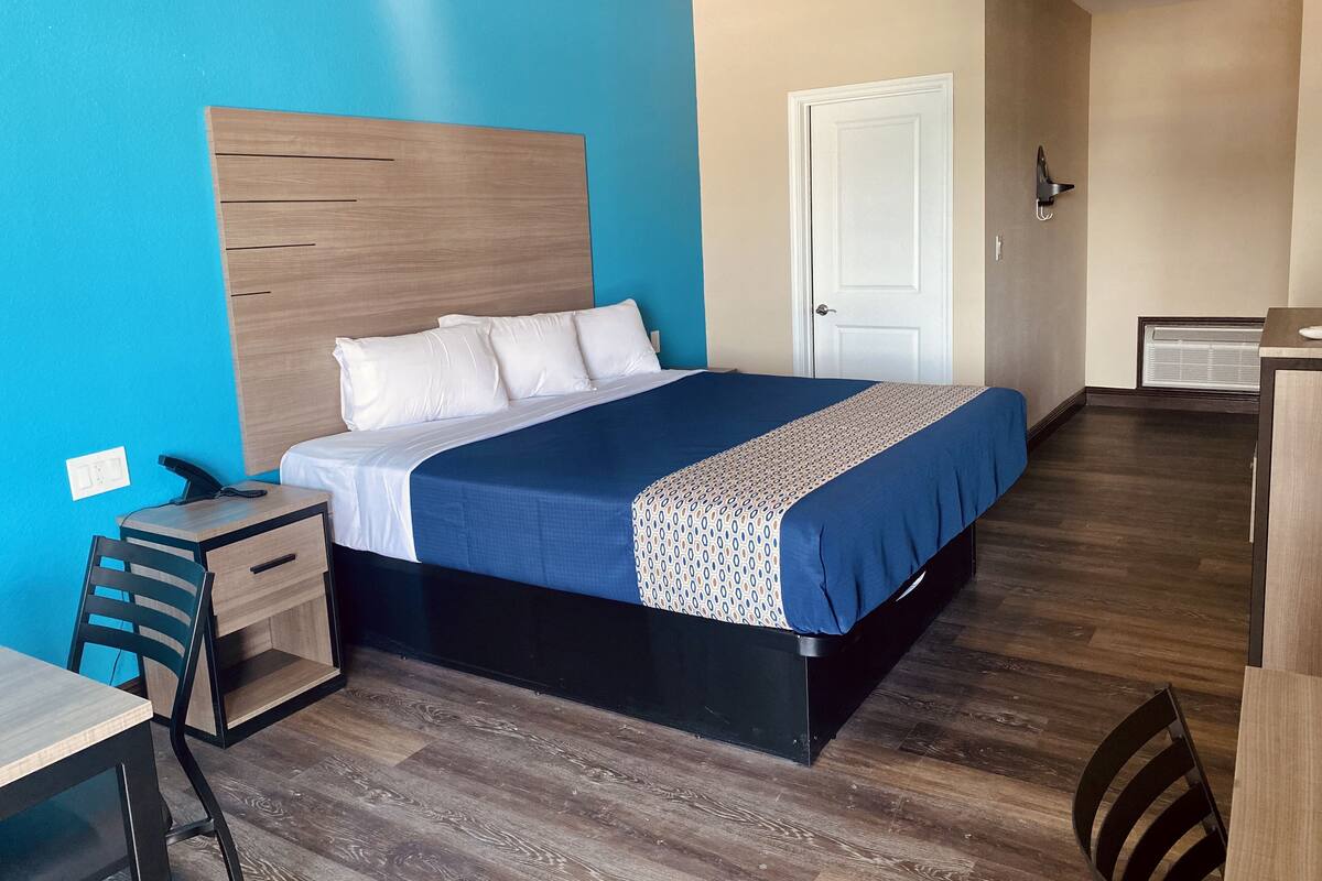 A hotel room with a bed, a desk, a chair, a wardrobe, and a door.