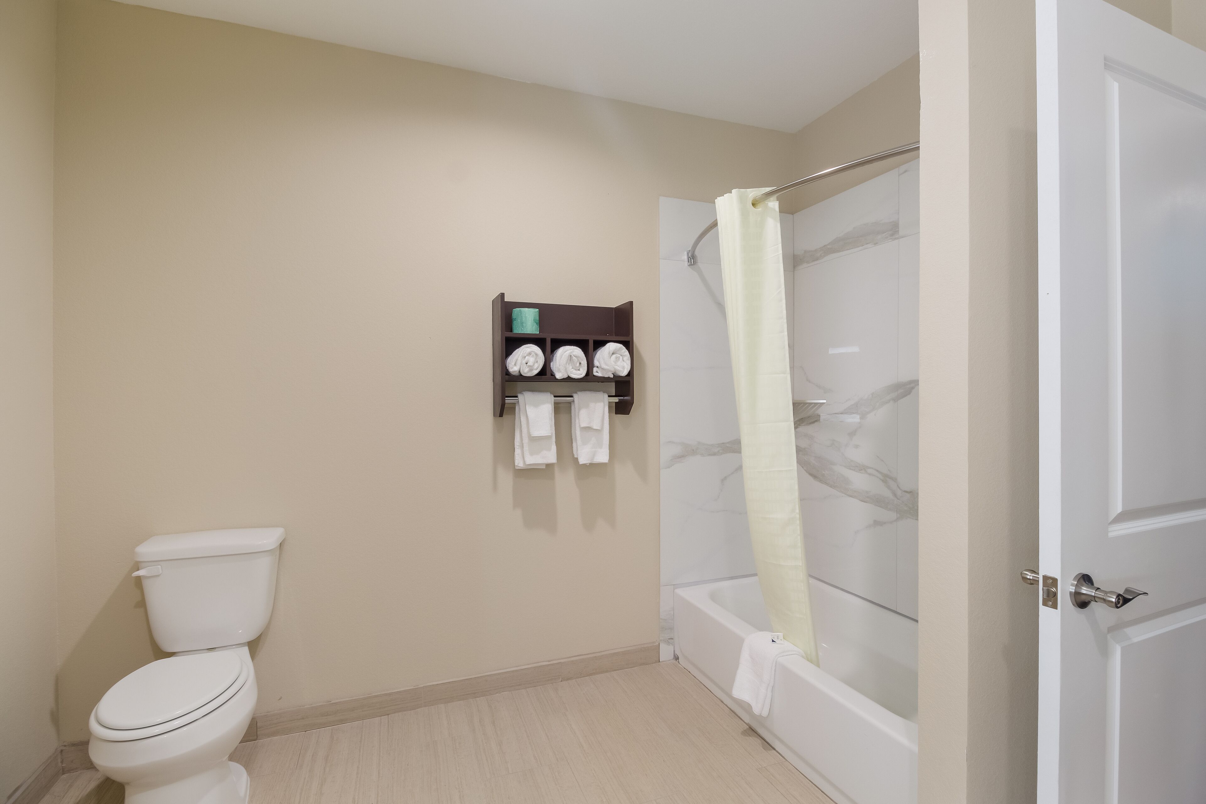 A bathroom with a toilet, a shower with a glass door, and a towel rack with towels.