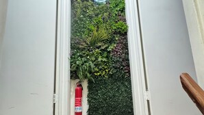 Un pasillo con pared de jardín vertical, un letrero de neón y un extintor.