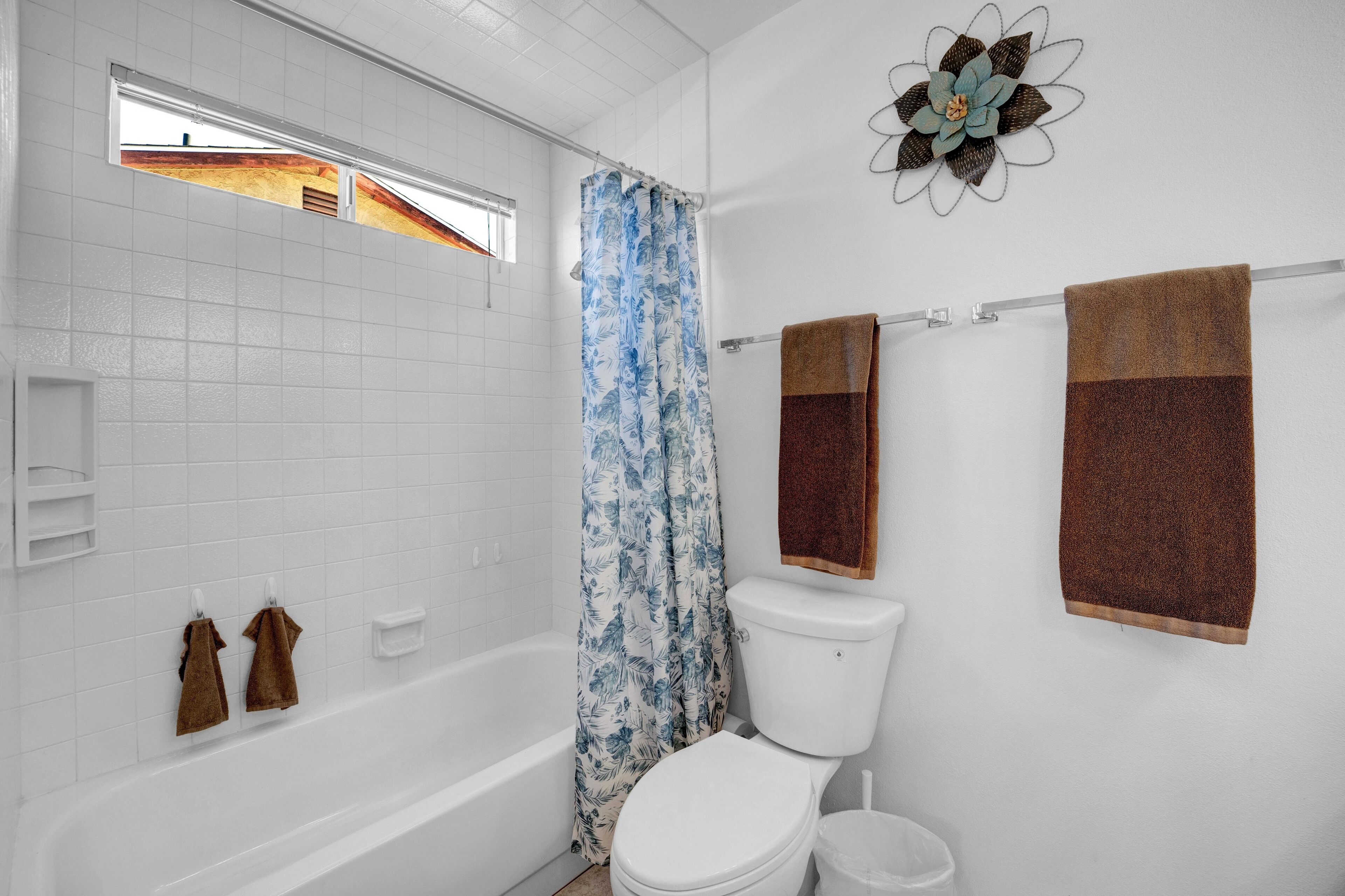 Een badkamer met bad, toilet, douchegordijn en handdoeken.