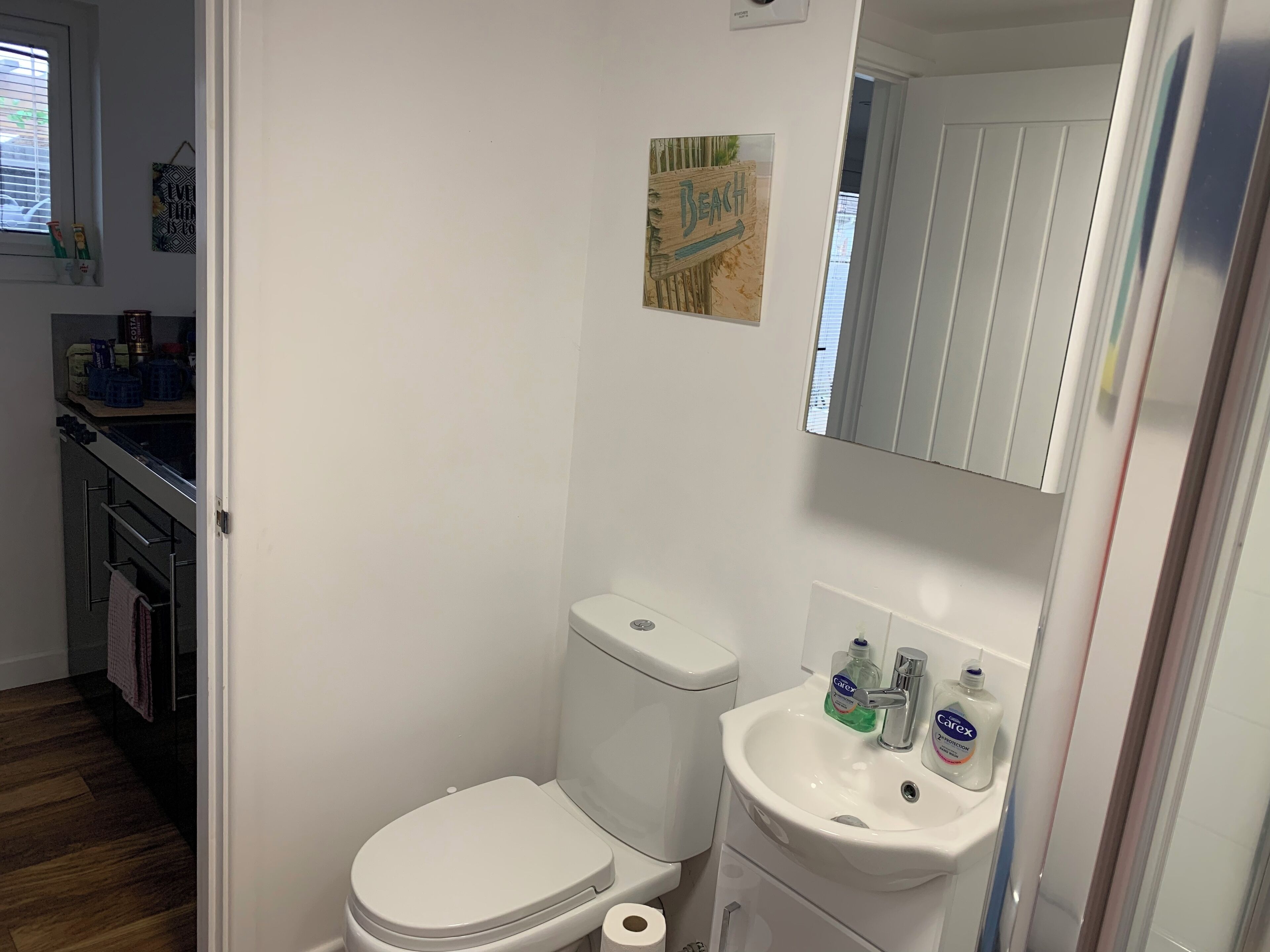 Un baño pequeño y funcional con inodoro, lavamanos y espejo.