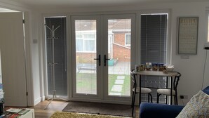 A living room with a sofa, a coffee table, and a door leading to a patio. - Lodge , air con , Free Parking , Mini bar (Hove)