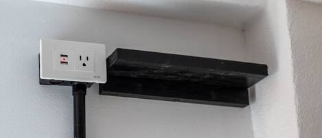 A white wall with a black electrical outlet and a black cable running along it.