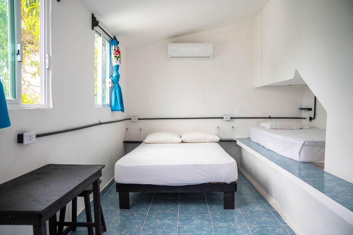 A small, clean room with a bed, a small table, and a bench.