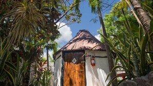 A small, rustic building with a thatched roof, surrounded by lush tropical vegetation. - Hostel Oryx Tulum (Tulum)