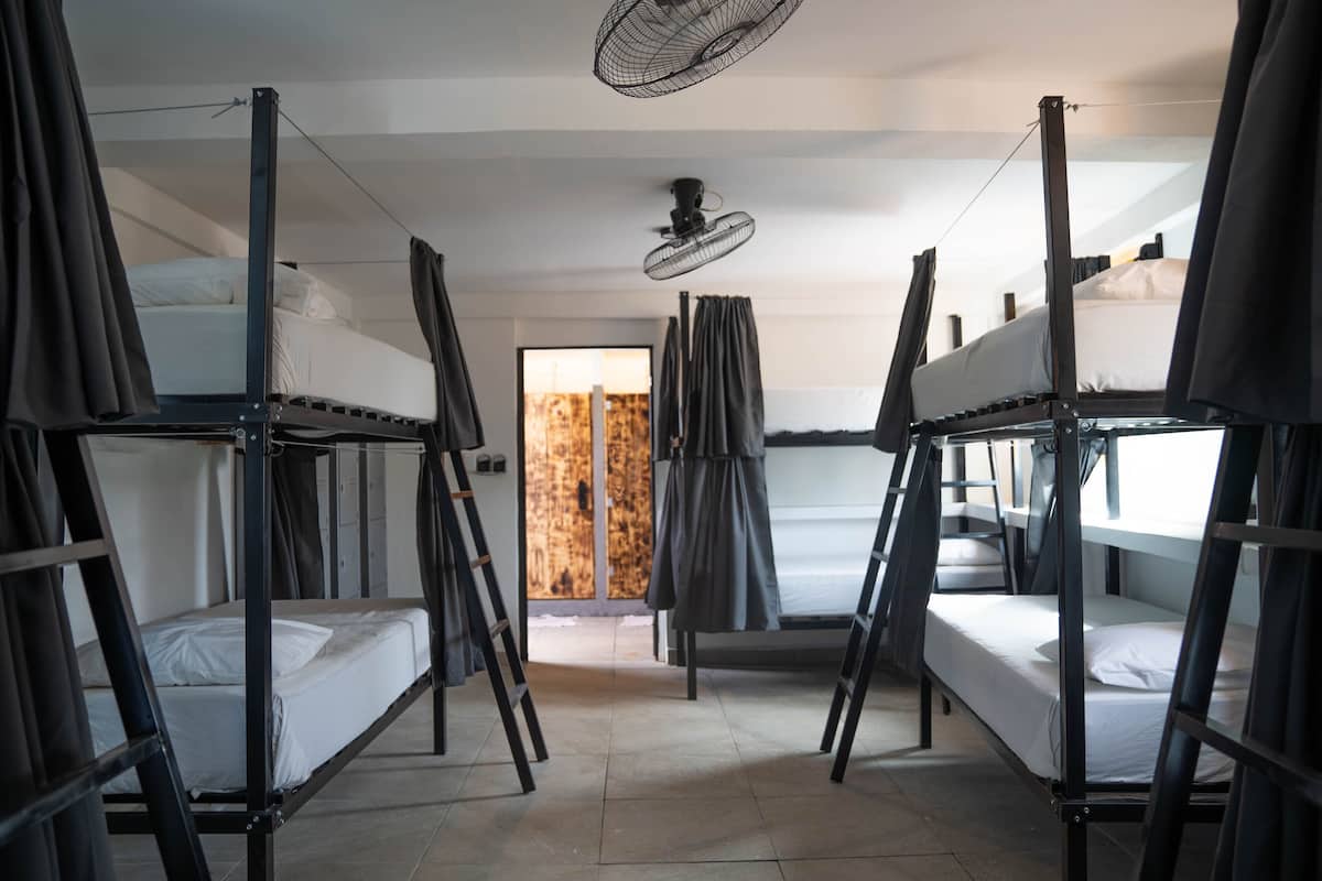A dormitory room with bunk beds, a ceiling fan, and a view of the outside.