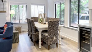 A dining area with a white table and patterned chairs, large windows, and a VISSANI refrigerator. - 9 Sandhill Crane at Sea Pines Resort (Hilton Head Island)