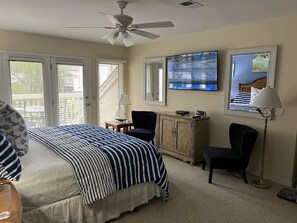Un dormitorio con cama, ventilador de techo, televisión, armario y una silla.
