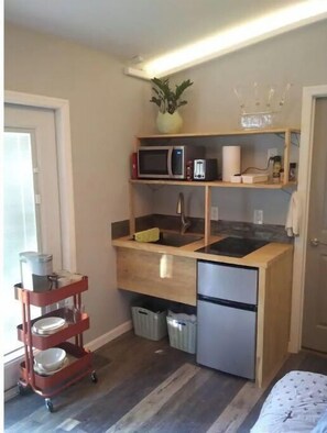 Compact kitchen with microwave, refrigerator, and sink, featuring ample workspace and additional storage.
