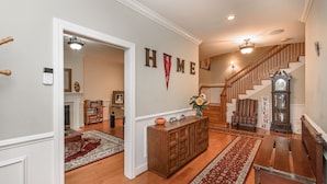 A spacious living area with a wooden bench, a fireplace, and a staircase leading to another level.