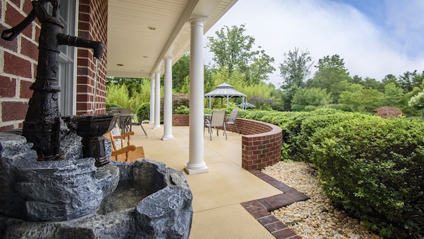 A covered patio with a stone fountain, outdoor seating, and a gazebo.