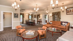 A spacious living room with a large sectional sofa, two armchairs, a coffee table, and a dining area with a table and chairs.