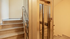 Una escalera con barandilla de metal que lleva a un ascensor.