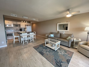 A living room with a sofa, coffee table, and a dining area with chairs and a kitchen in the background. - Stay and Relax at Finns Up! Wonderful views of the Pamlico Sound (HATTERAS)