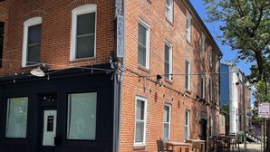 Un edificio de ladrillo con un letrero de 'cerrado', mesas al aire libre y un cartel de 'prohibido estacionar'.