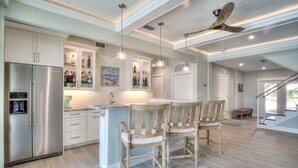 Una cocina moderna con una isla central, sillas de madera y un ventilador de techo.