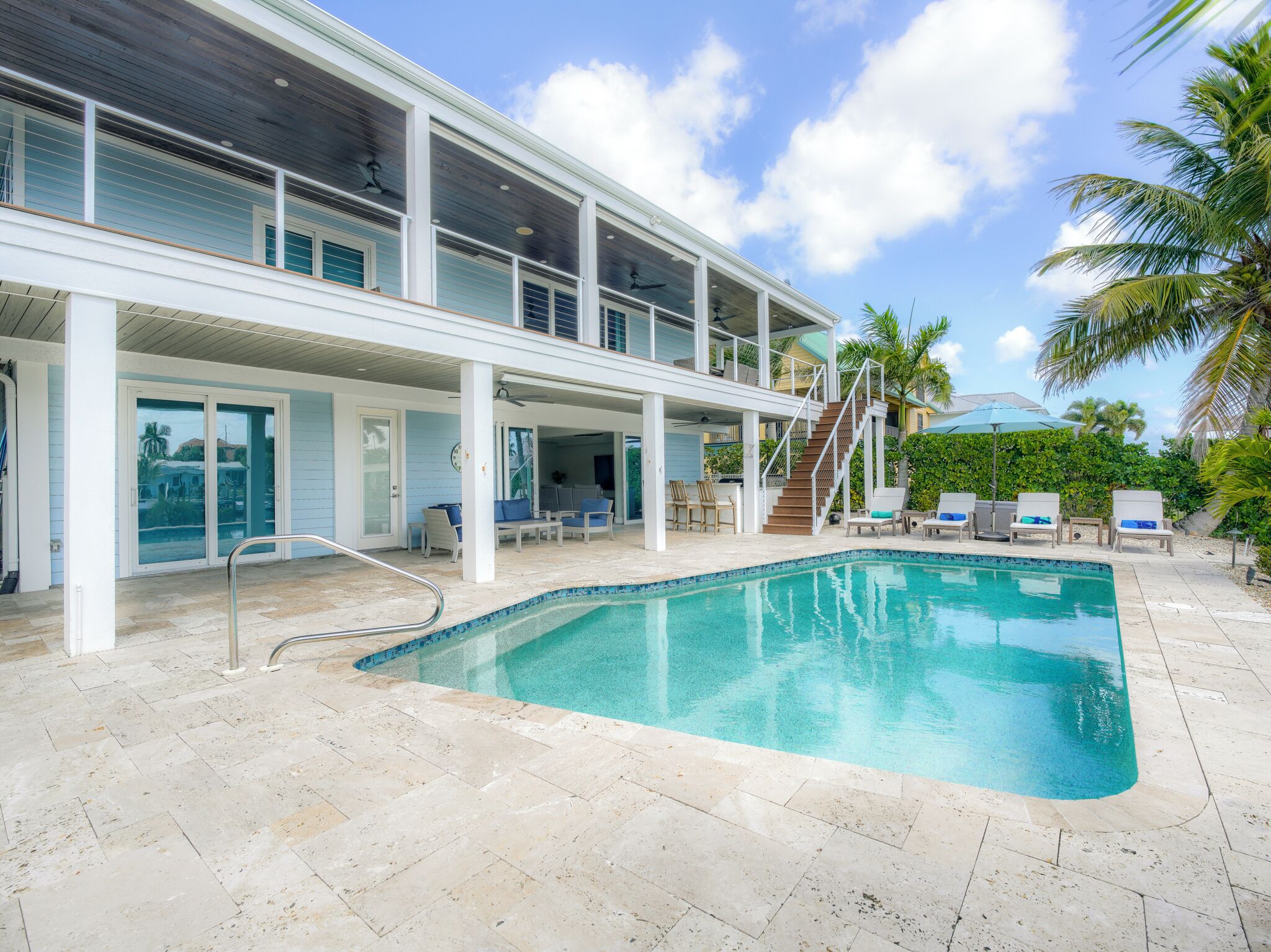 A two-story house with a swimming pool, outdoor seating, and a covered patio area.