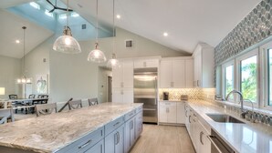 Una cocina moderna con una isla grande, electrodomésticos de acero inoxidable e iluminación colgante.