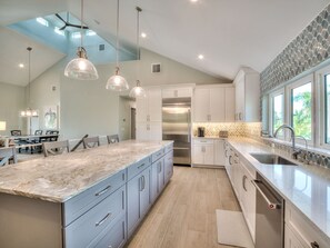 A modern kitchen with a large island, stainless steel appliances, and pendant lighting. - Luxury 5 Bedroom Coastal Retreat (Fort Myers Beach)