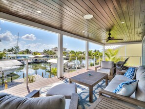 A covered outdoor area with a wooden deck, seating, and a view of a marina with boats. - Luxury 5 Bedroom Coastal Retreat (Fort Myers Beach)
