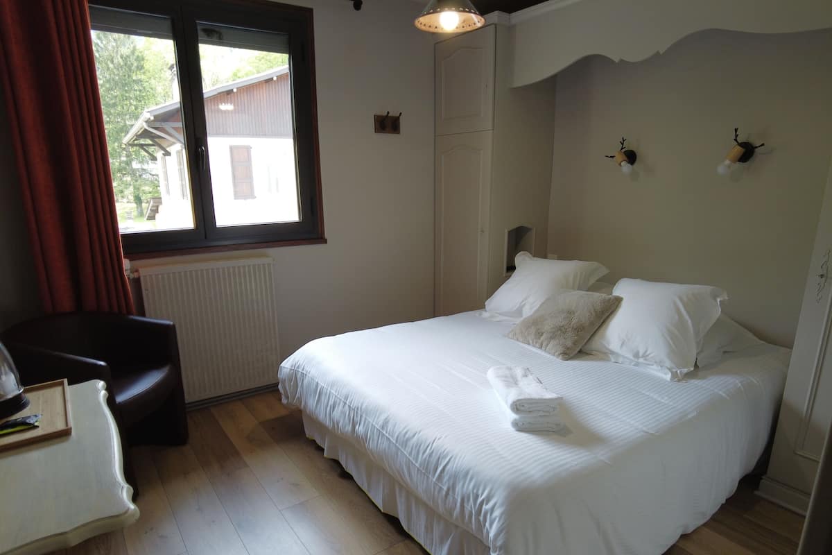 A neatly arranged bedroom with a bed, a chair, and a desk.