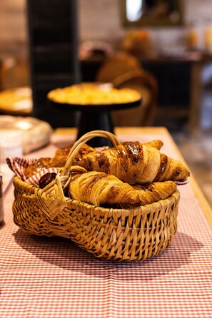 A wicker basket filled with croissants on a checkered tablecloth.
