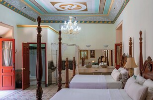 Una habitación de hotel con una cama grande, un área de descanso, un baño y un candelabro.