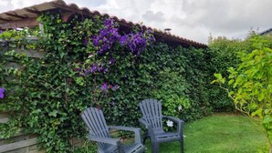 Two Adirondack chairs in a garden with a wooden fence and lush greenery. - Le Clos du Savourey, charming Normandy farmhouse, sleeps 6 (Saint-Aubin-de-Scellon)