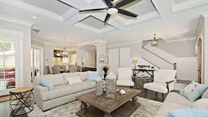 A spacious living room with a high ceiling fan, a wooden coffee table, and a large window offering a view of the outdoors. - 12 Green Heron at The Sea Pines Resort (Hilton Head Island)