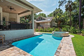 Un patio trasero con piscina, bañera de hidromasaje y terraza cubierta.