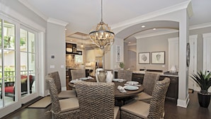 A dining area with wicker chairs, a chandelier, and a view of the kitchen. - 12 Green Heron at The Sea Pines Resort (Hilton Head Island)