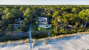 A large estate with multiple buildings surrounded by dense forest and beachfront.