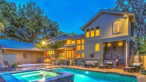 A two-story house with a swimming pool, outdoor seating, and a well-lit patio area.