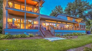 A modern two-story house with large windows, a covered porch, and a well-maintained lawn.