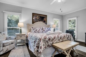 A bedroom with a bed, two nightstands, a chair, a table, and two windows with blinds. - 19 Bald Eagle West at The Sea Pines Resort (Hilton Head Island)
