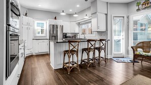 A modern kitchen with white cabinetry, stainless steel appliances, and a central island with bar stools.