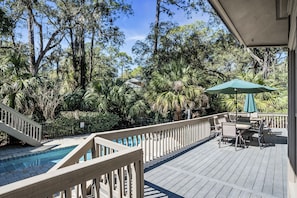 A wooden deck with a pool, surrounded by tropical vegetation and a dining area with outdoor furniture. - 19 Bald Eagle West at The Sea Pines Resort (Hilton Head Island)