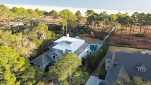 An aerial view of a house with a large backyard, a swimming pool, and a view of the ocean.