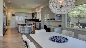 A modern kitchen with a central island, bar stools, and a dining table with a decorative plate.