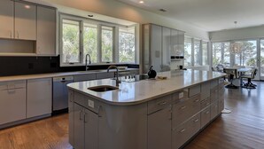 A modern kitchen with a large island, built-in appliances, and large windows offering natural light.
